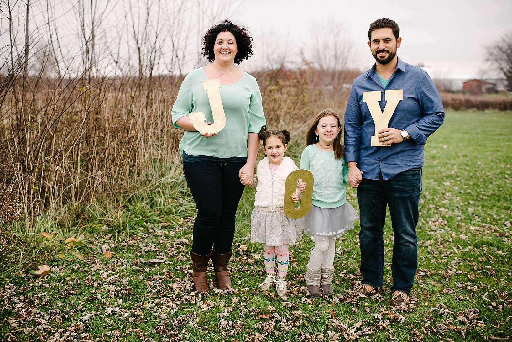 parents and two daughters holding hands and letters spelling JOY