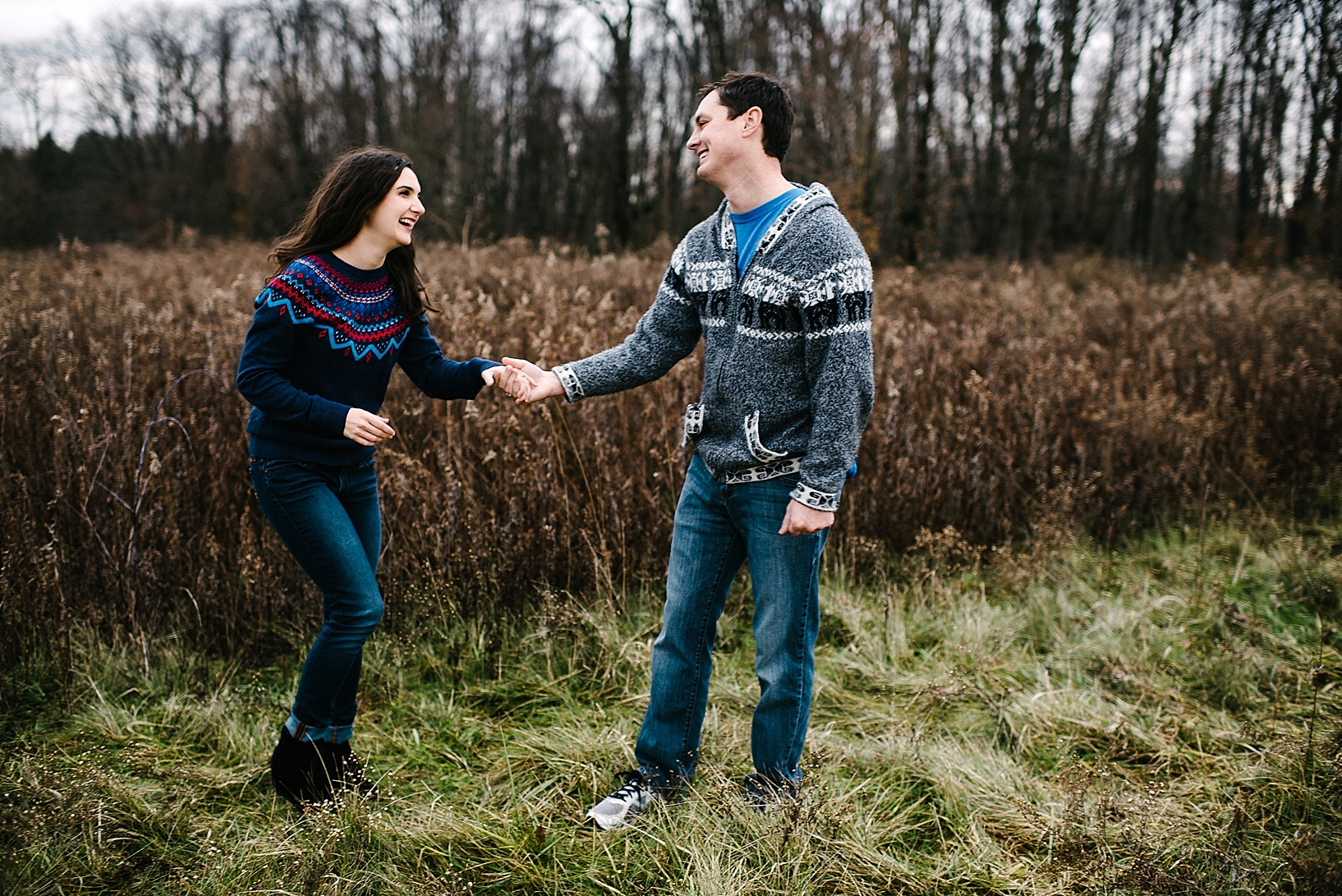 couple holding hands and smiling at each other in winter field