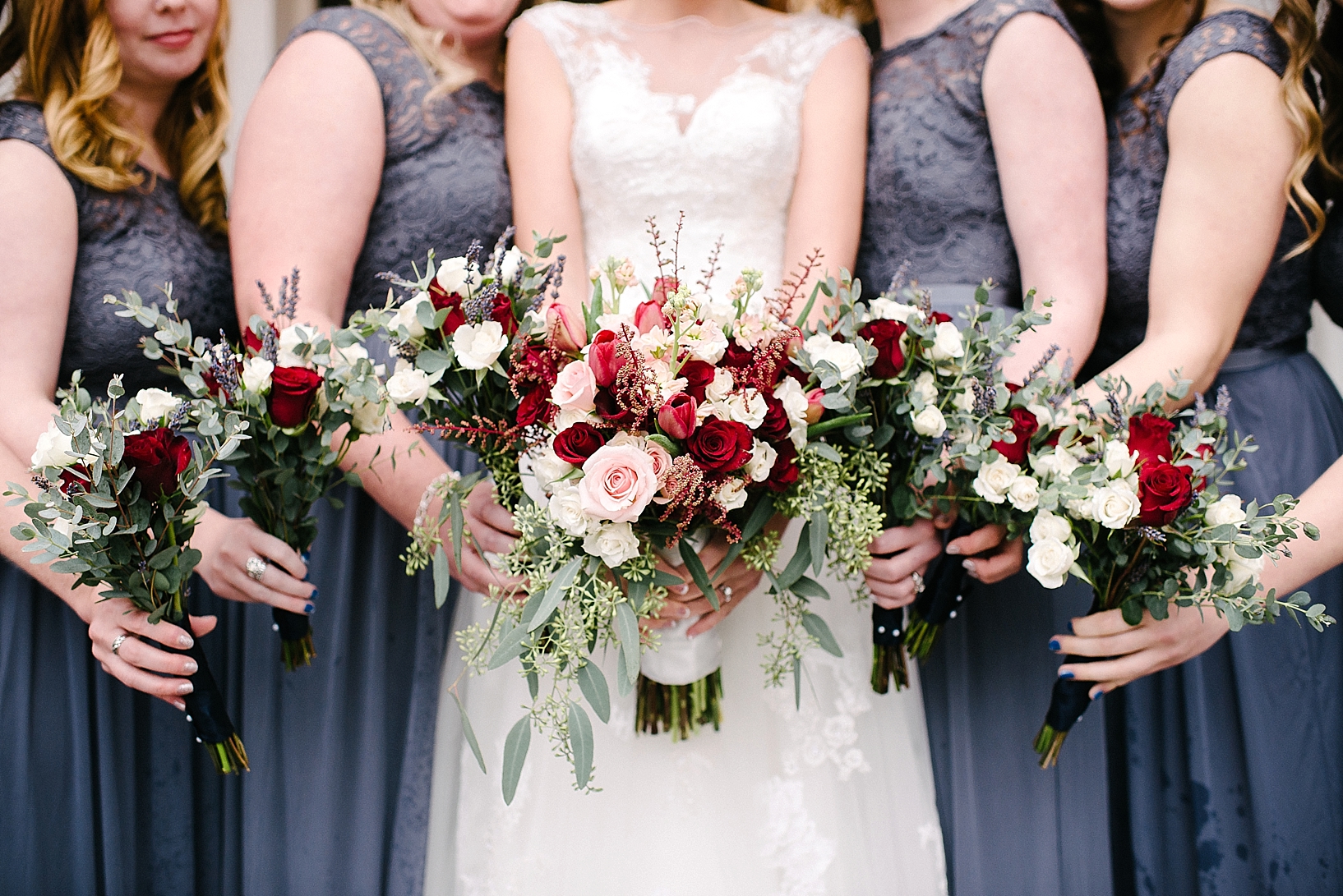 bridesmaids in gray lace dresses holding winter bouquets of burgundy, pink, and white roses