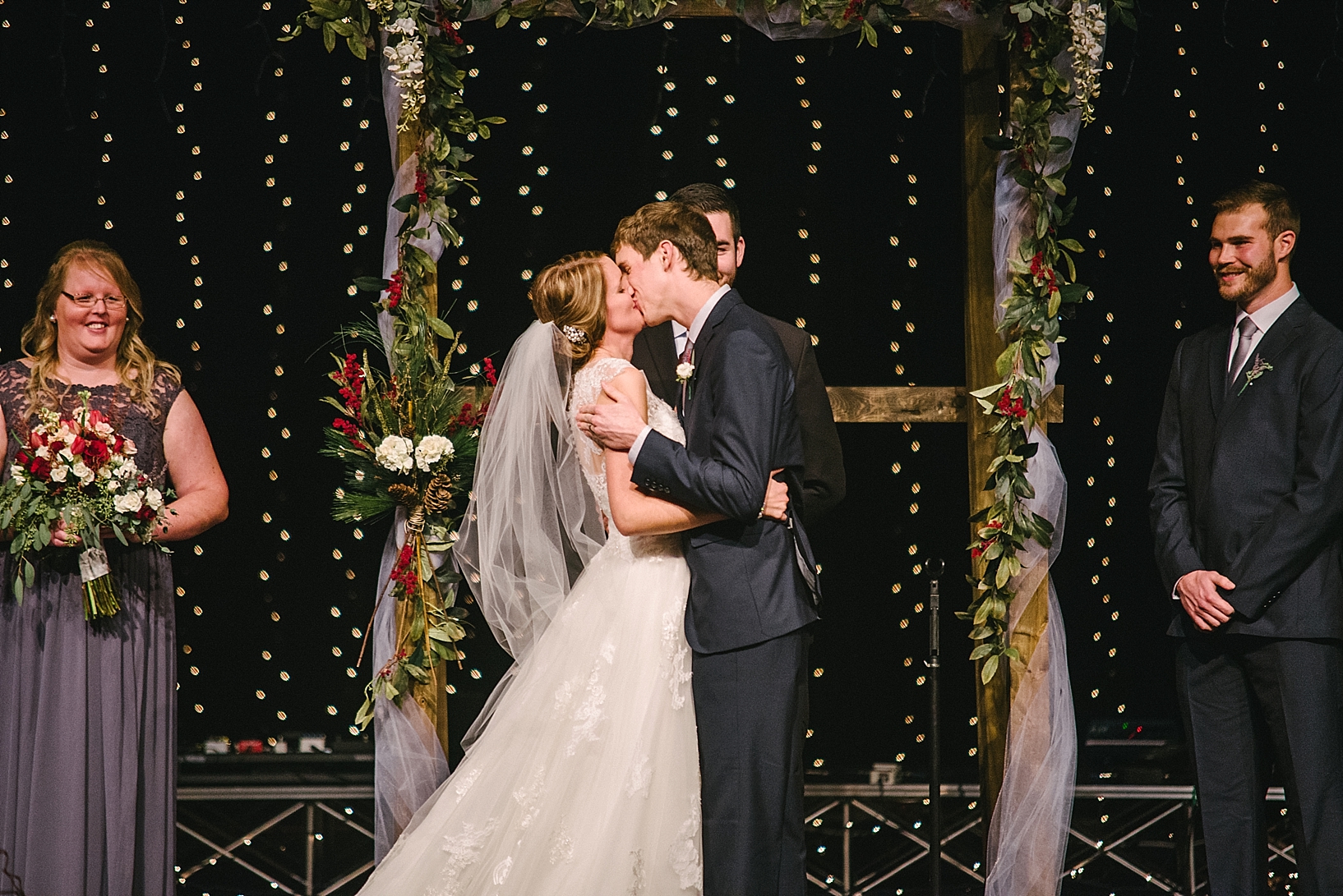 bride and groom share first kiss during wedding ceremony on church stage