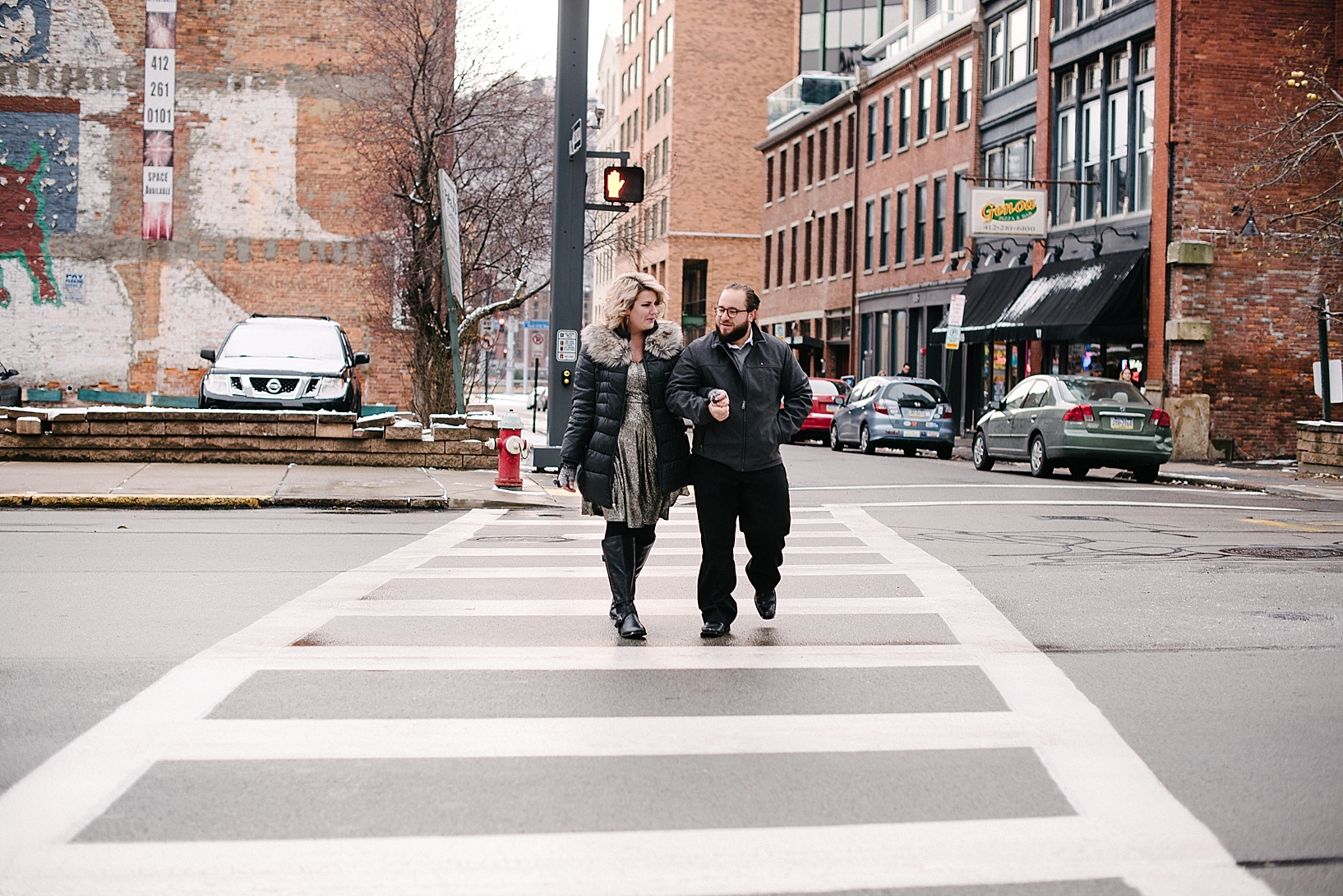 couple linking arms crossing downtown city street in winter