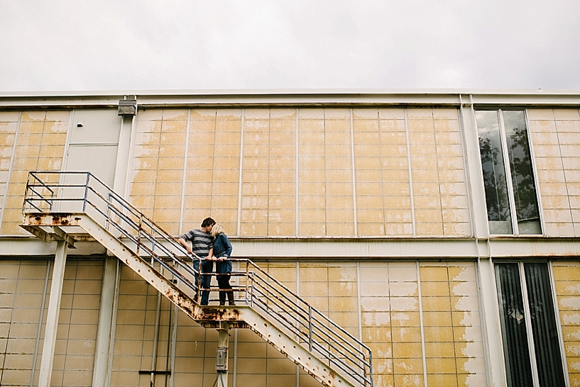 couple standing on fire escape on yellow building