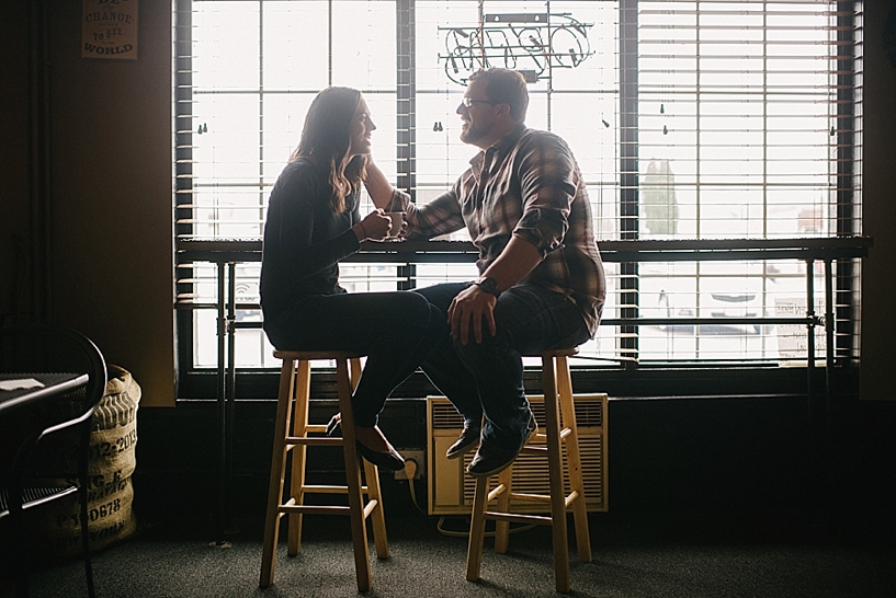 couple sitting on bar stools in coffee shop talking
