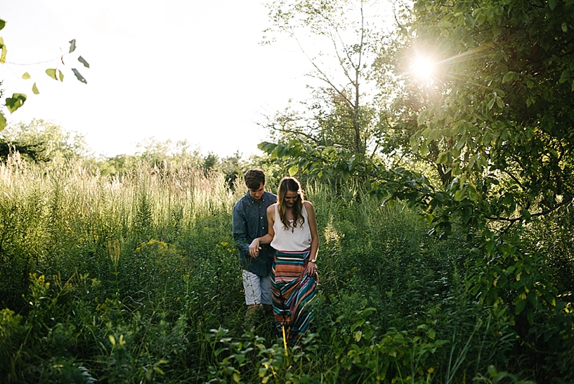 couple walking through field with sun shining