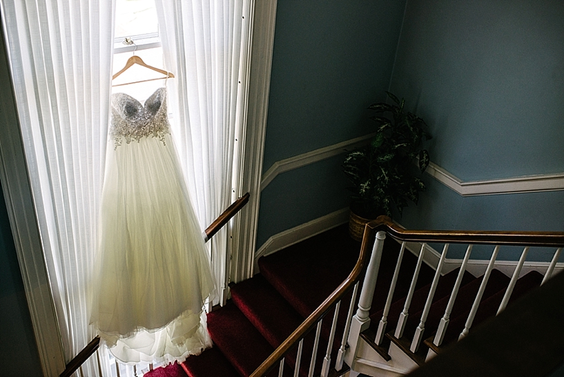 wedding gown hanging on window by staircase