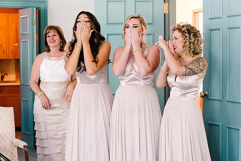bridesmaids in blush dresses react to seeing bride for the first time