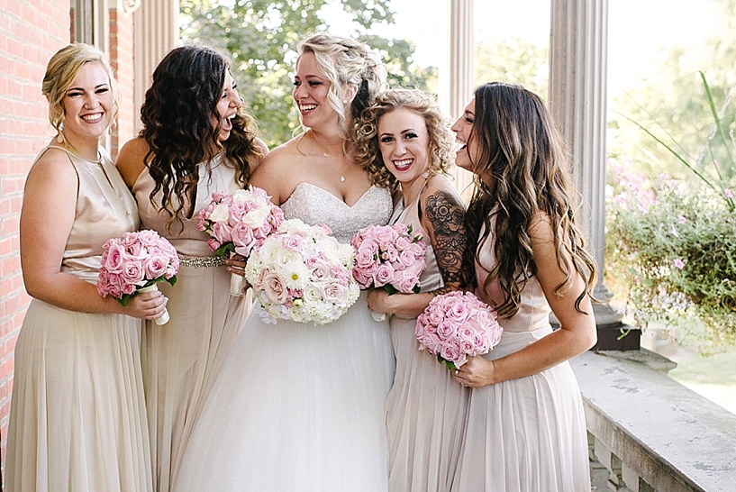 bridesmaids in blush and champagne hugging bride