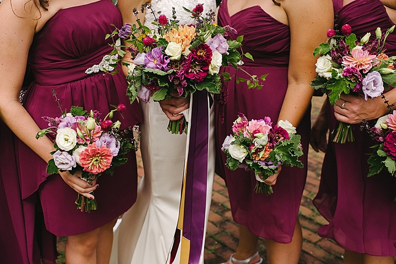 bridesmaids wearing wine colored dresses holding wildflower bouquets