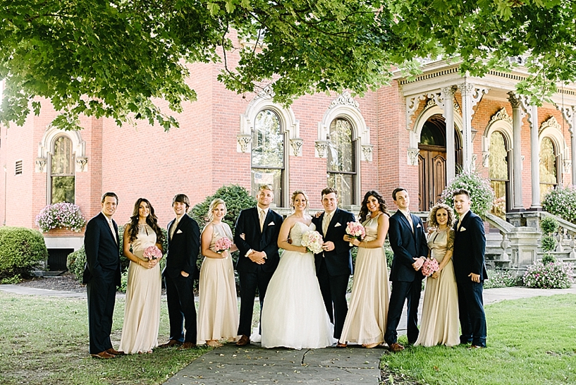 formal bridal party in front of brick mansion