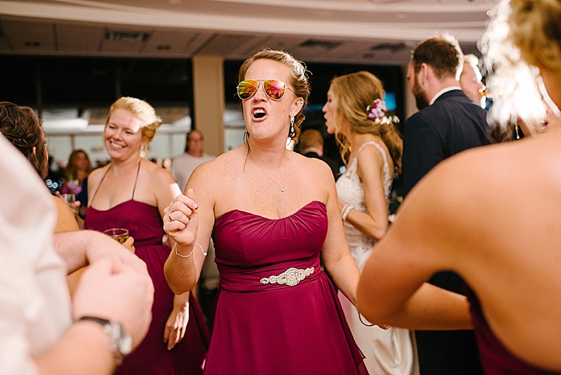 bride in wine dress and sunglasses dancing and singing on dance floor