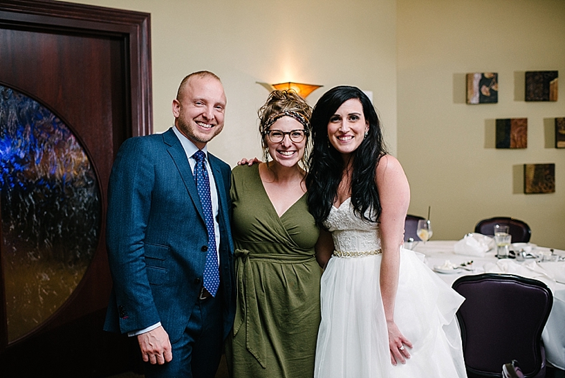 bride and groom standing with girl in green dress