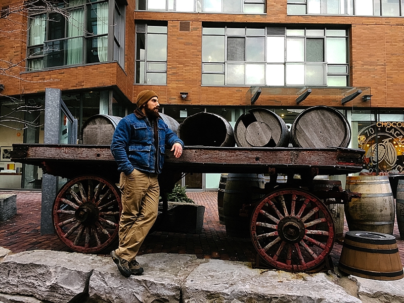 man standing in front of barrels in the Distillery District of Toronto