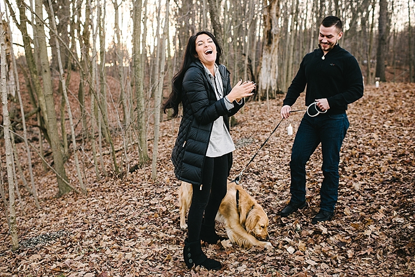 couple standing in woods smiling and laughing after getting engaged