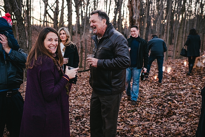 family members smiling and drinking champagne outside in woods