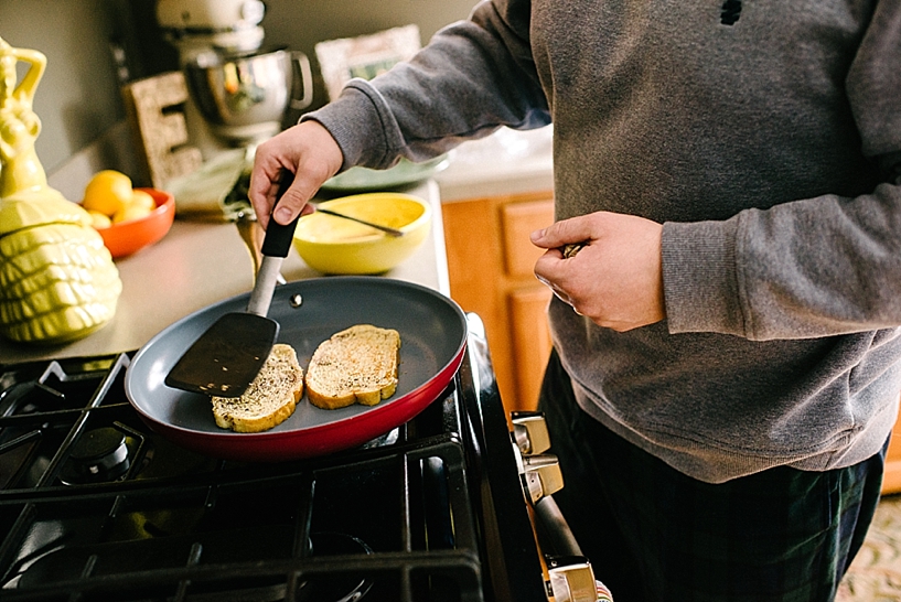 man in grey sweatshirt making french toast in red skillet