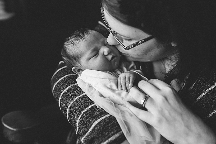 mother holding newborn baby in her arms kissing her cheek