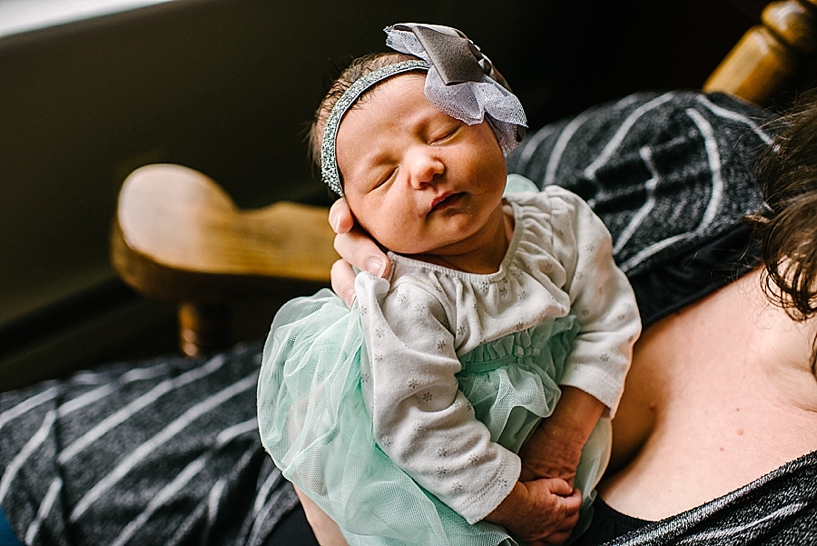 newborn girl in teal tutu and headband in mother's arms