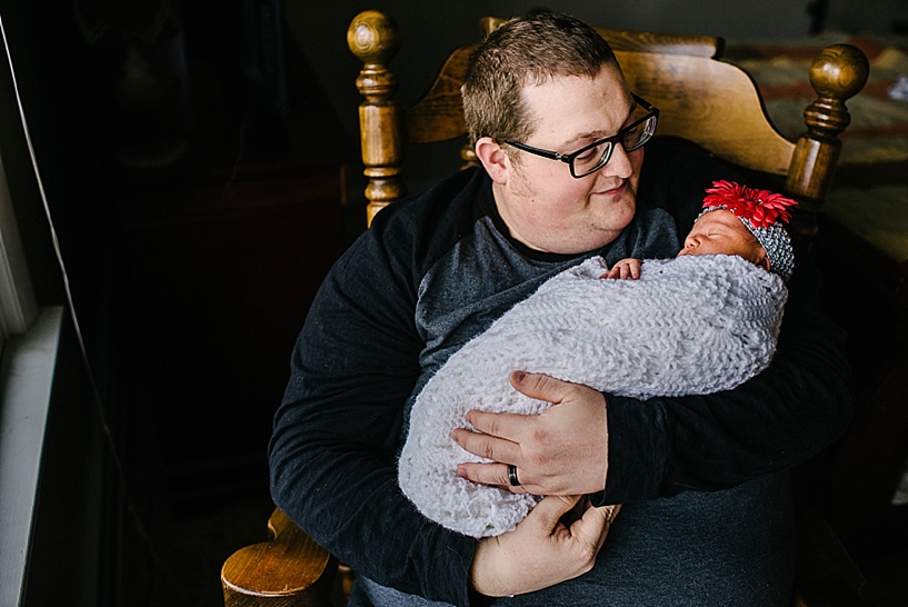 proud father rocking newborn daughter wrapped in lace blanket
