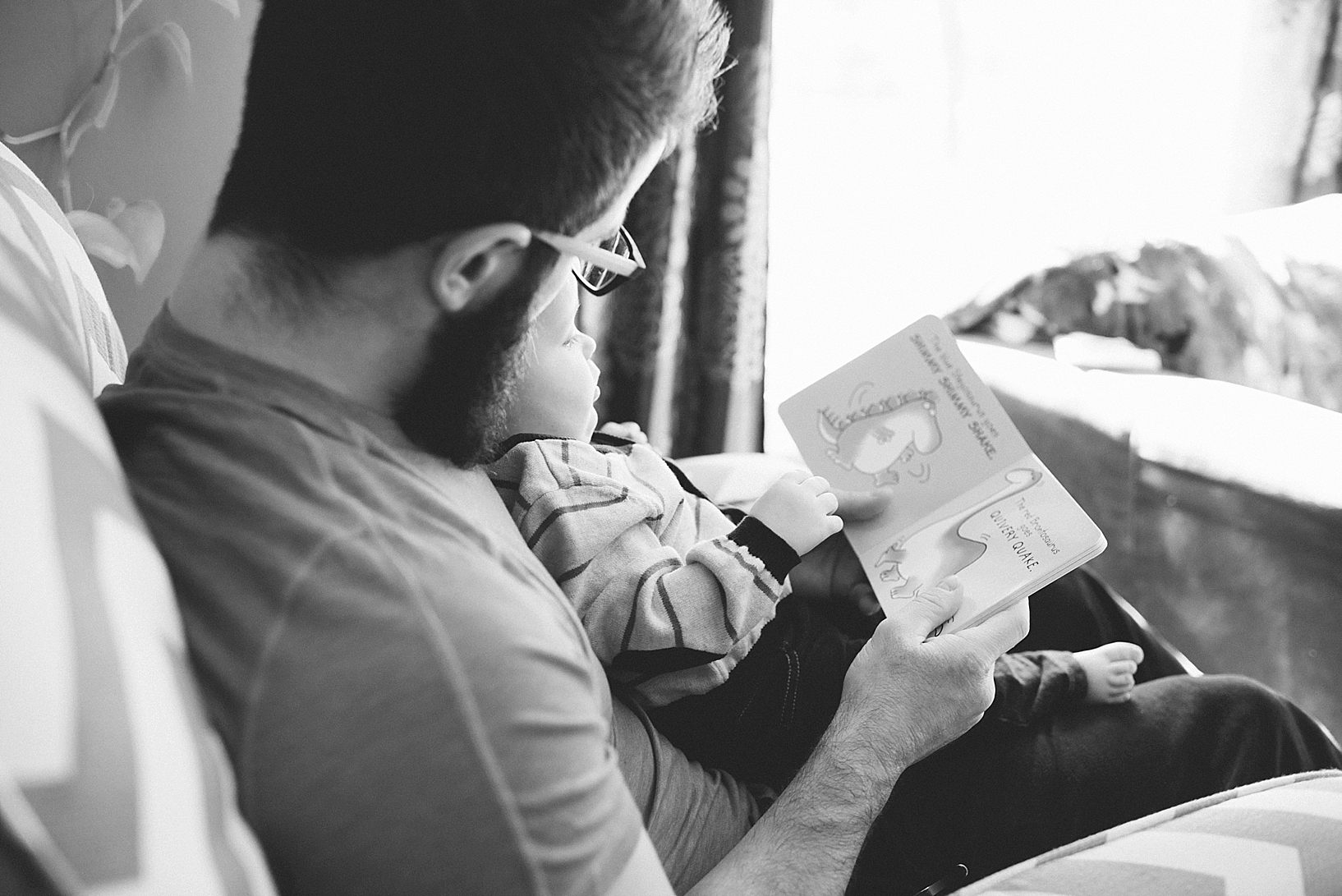 dad holding son on lap reading book