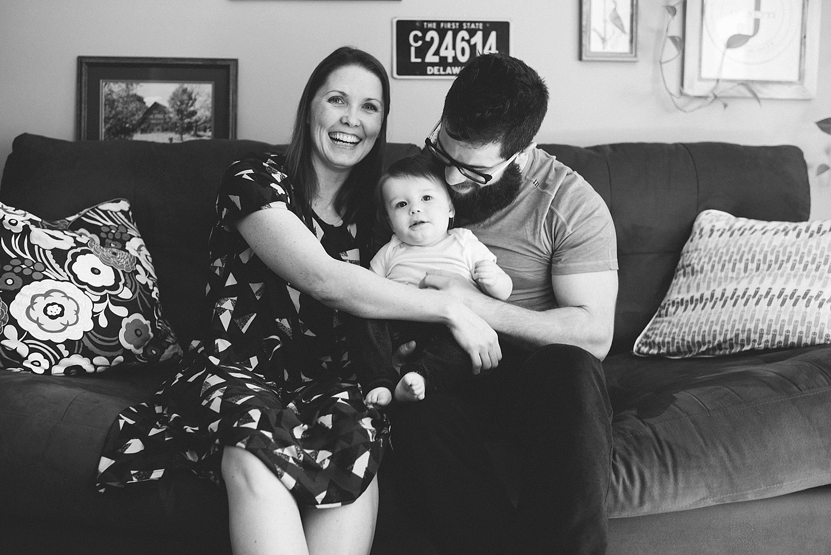 mom in Lularoe dress and dad holding young son on their laps sitting on couch