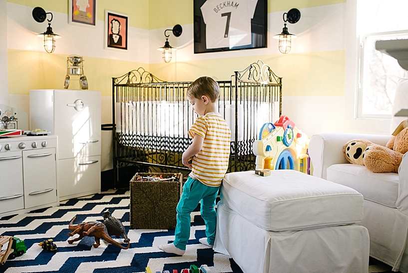 little boy playing in bedroom with yellow and white striped walls