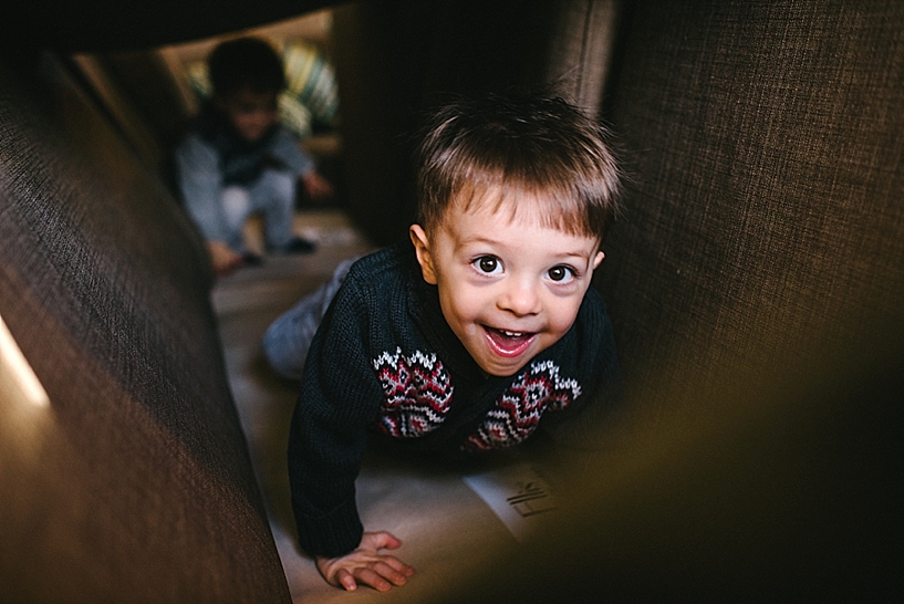twin toddler boys climbing through couch fort