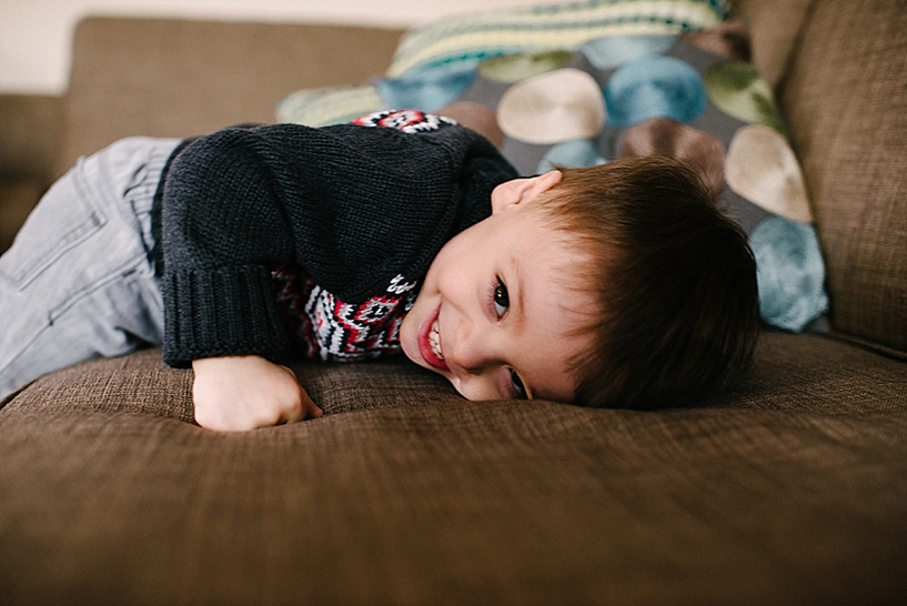 toddler boy laying on couch laughing