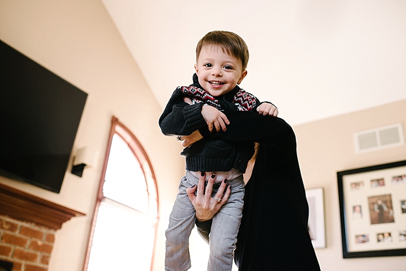 mom swinging toddler boy in the air in living room