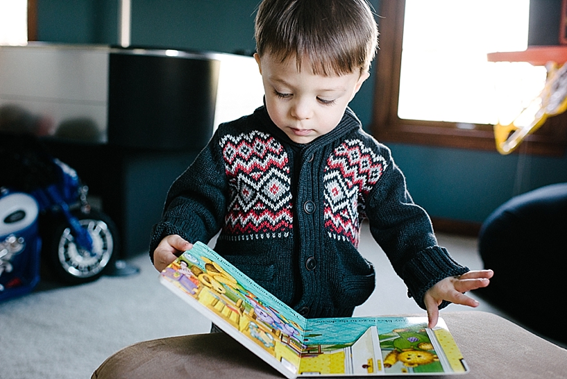 toddler boy wearing navy sweater reading children's book