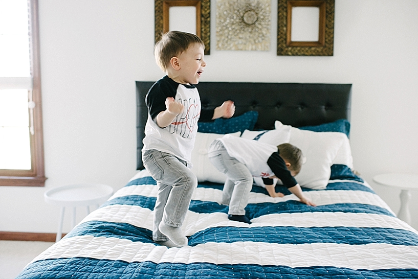 twin toddler brothers jumping on bed laughing