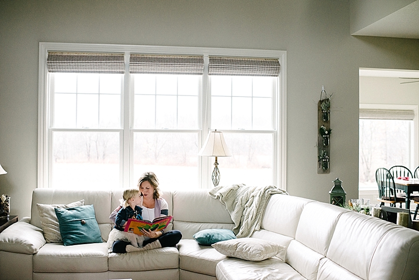 mother and daughter sit on couch reading book