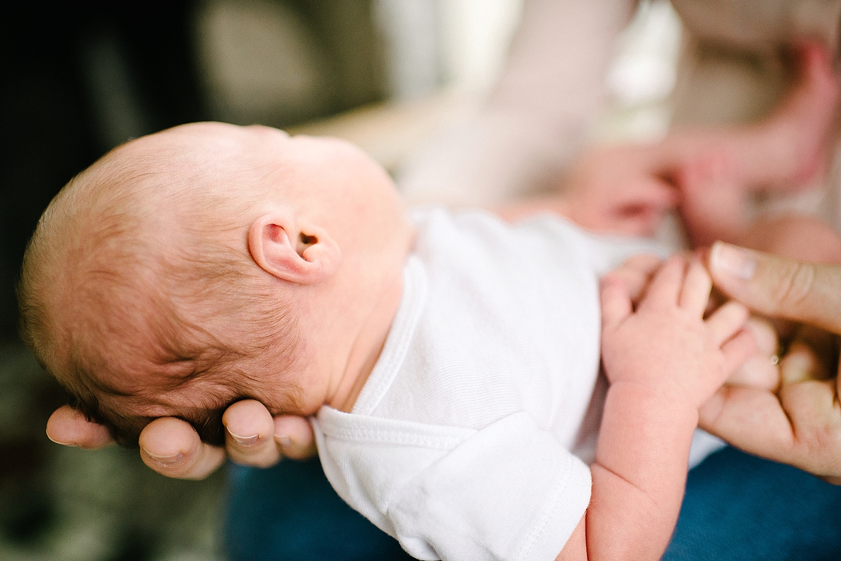 newborn baby in white onesie in mother's hands