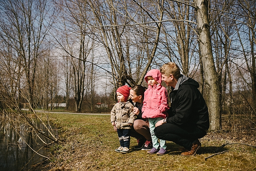 mom and dad kneeling next to young son and daughter by pond