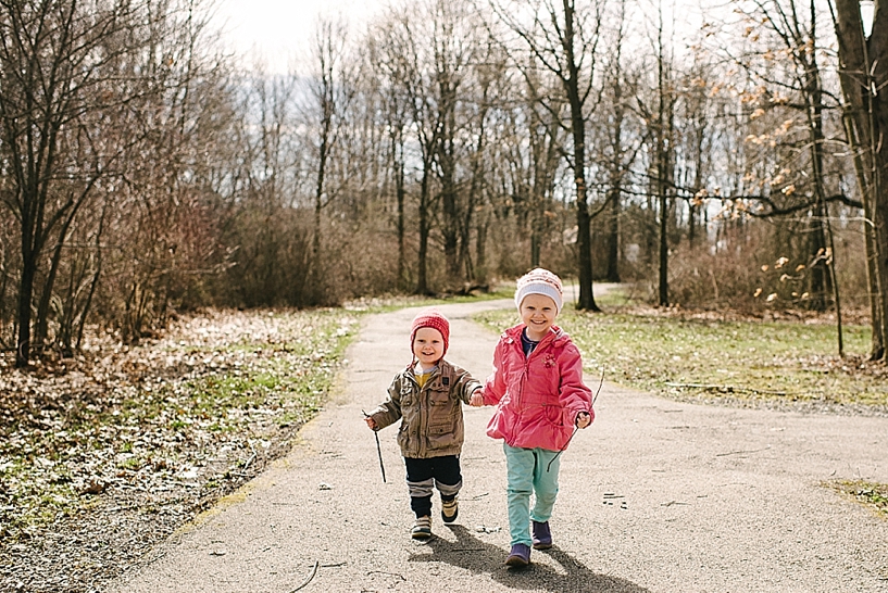 young boy and girl walking hand in hand through woods