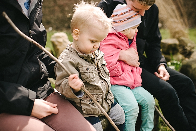 family sitting on park bench with young kids