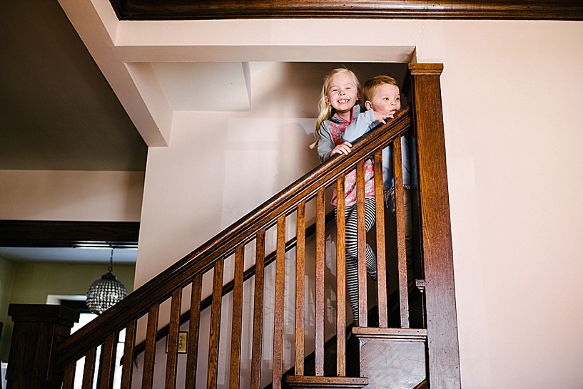 little boy and girl standing at top of staircase peeking over railing