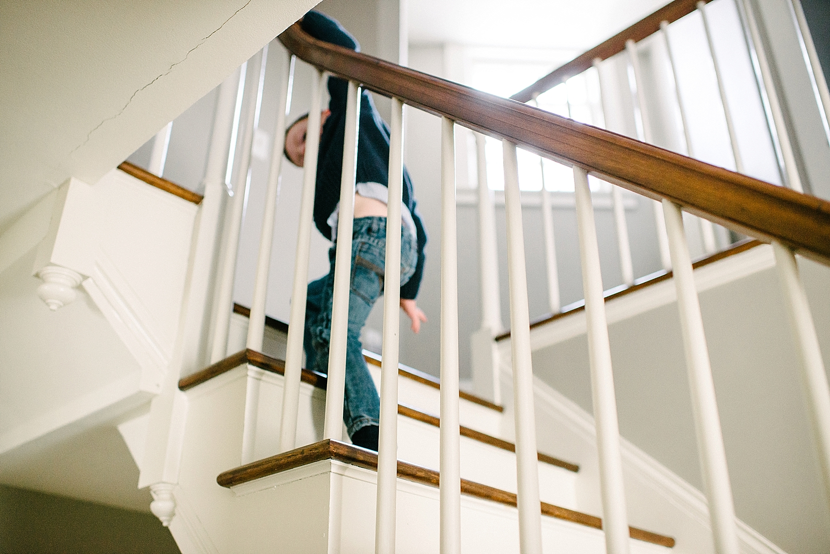 young boy climbing up staircase of old home