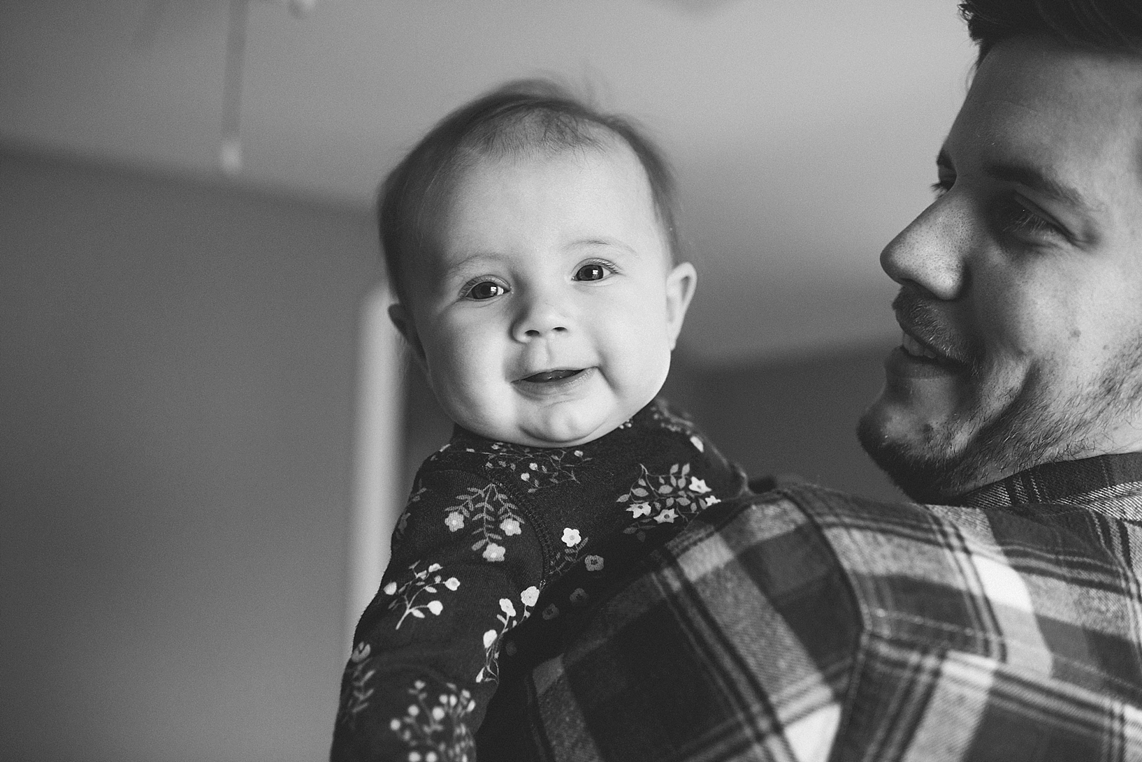 baby girl looking over dad's shoulder smiling