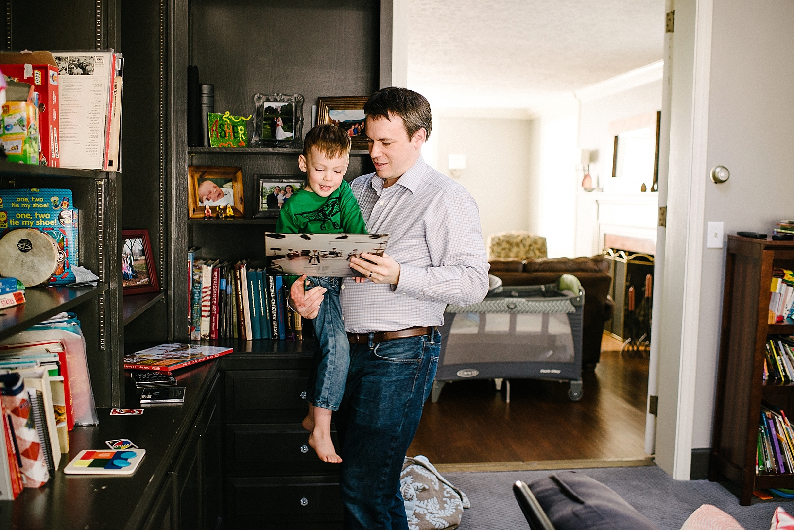 man holding son in living room looking at records