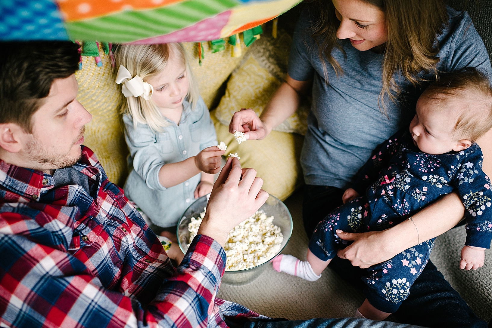 family eating popcorn in living room blanket fort