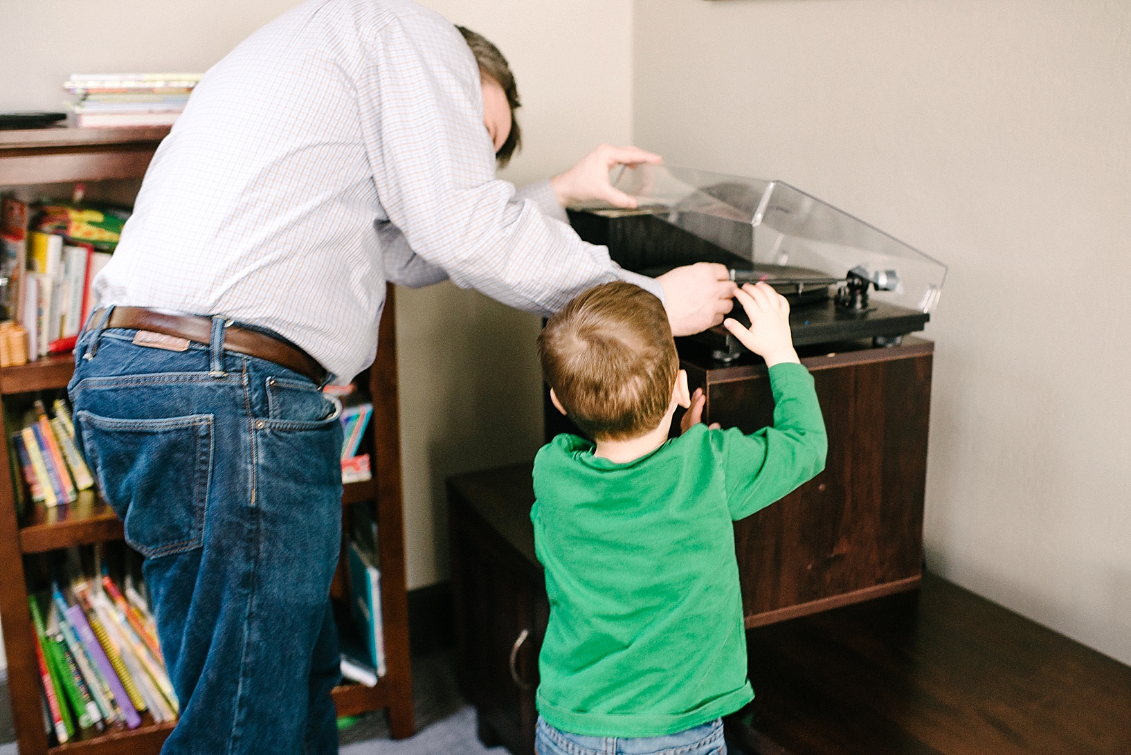 man and son putting needle on record player