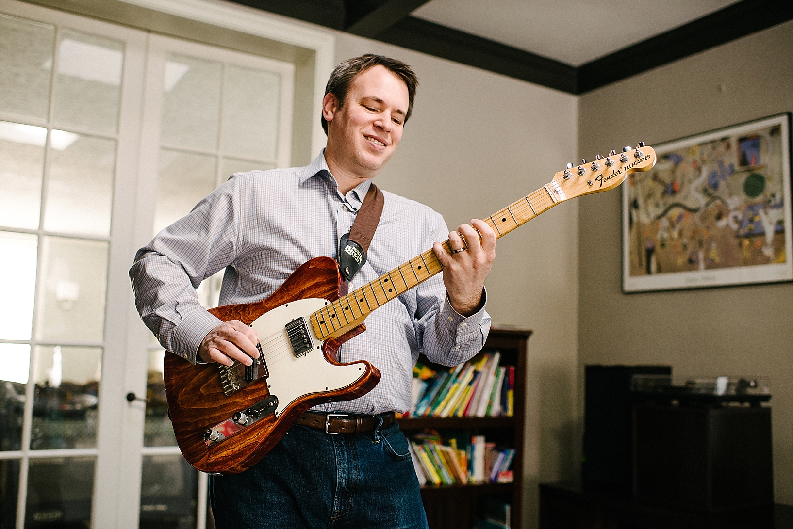 man playing electric guitar in living room