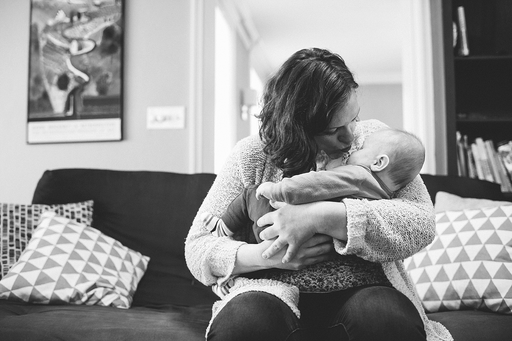 woman holding infant in her arms sitting on couch