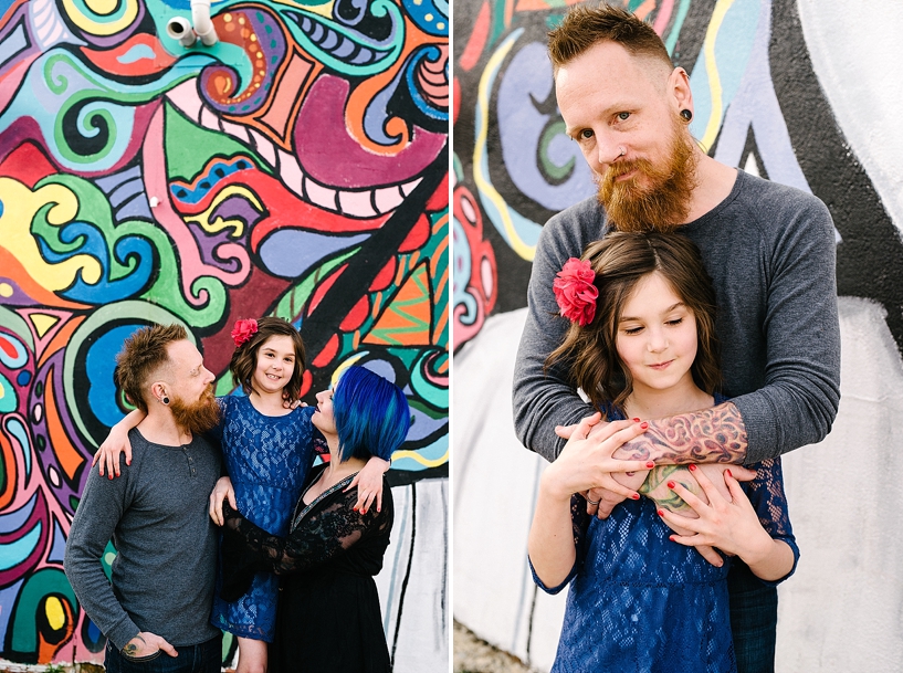 bearded dad with tattoos hugging young daughter in front of colorful graffiti mural