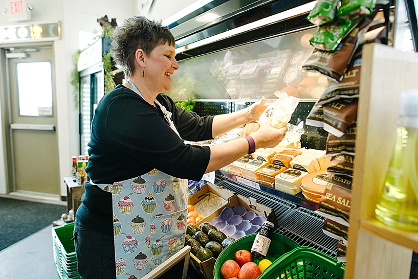 woman stocking produce shelves of grocery store 