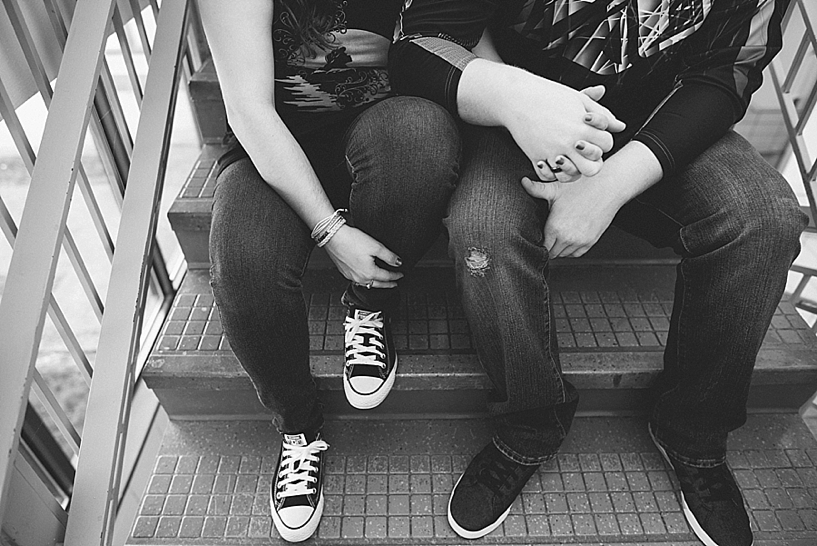 couple sitting on steps inside high school holding hands