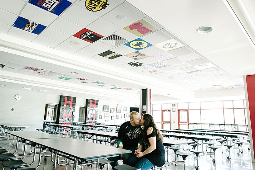 couple sitting in empty high school cafeteria kissing