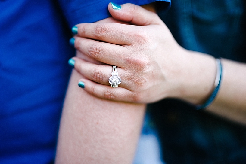 diamond engagement ring on woman's hand with blue painted nails