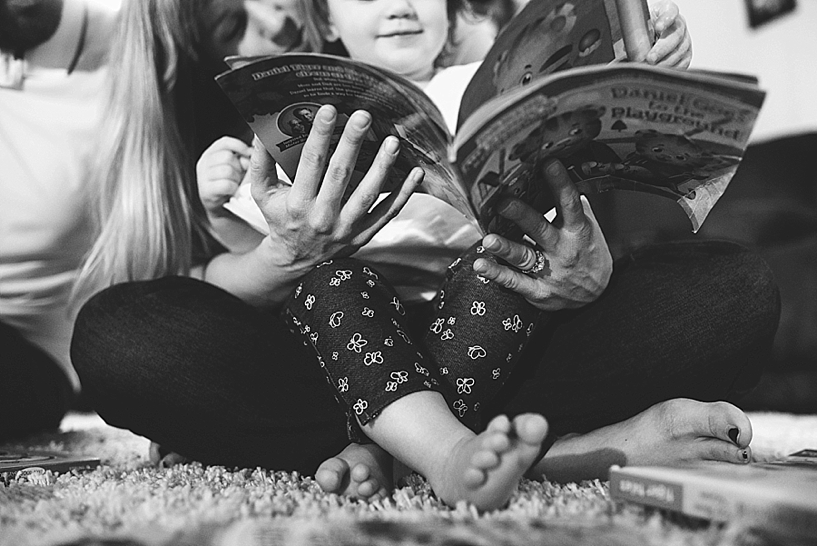 girl sitting in mother's lap reading book