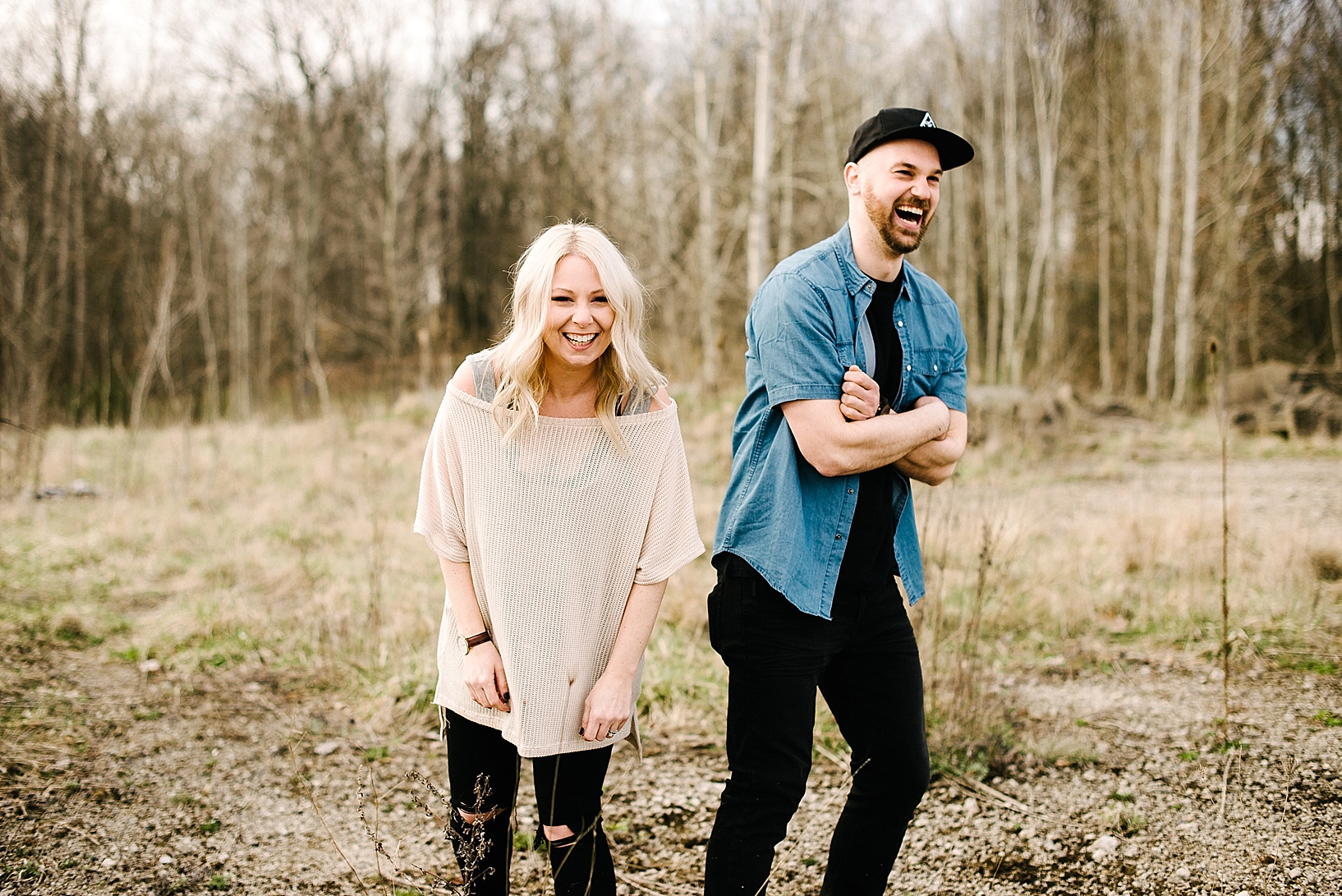 man and woman standing outdoors in field laughing